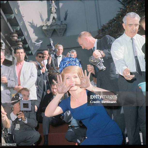 Color on actress Debbie Reynolds putting her handprints, footprints, and autograph in cement in the patio of the Grauman's Chinese theater in...