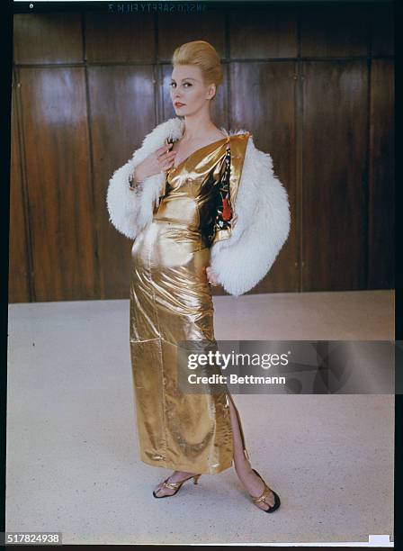 Fine 'n dandy. New York. Gold lavishly is molded to the feminine figure with this evening costume designed by Samuel Robert, leather couturier. The...