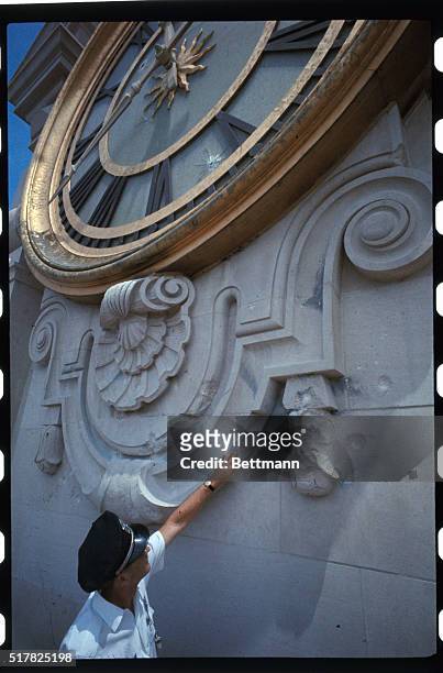 University of Texas policeman Earnest R. Puryear points to bullet holes in tower building clock, from which sniper Charles Whitman staged a wild...