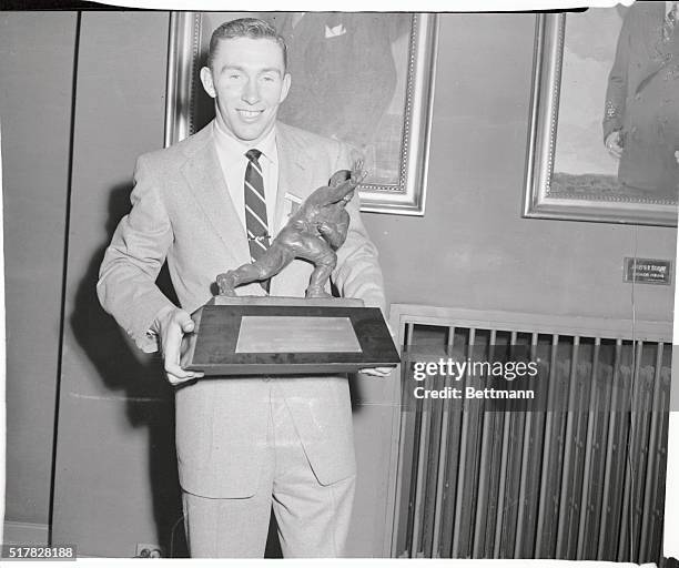 Johnny Lattner, Notre Dame's two-time All-American halfback, proudly displays the Heisman Memorial Trophy awarded to him today at the Downtown...