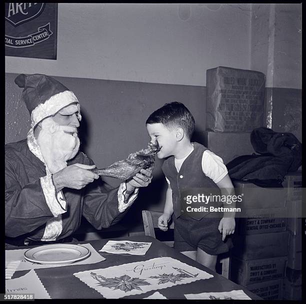 New York, New York- After a busy day of deliveries on Christmas Eve, Santa and Andrew Murray enjoy a bit of turkey leg at the Salvation Army Center.