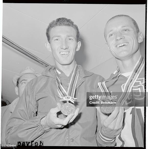 Tokyo, Japan: Bob Schul, of the United States is at the left with a gold medal, and his teammate Bill Dellinger holds a bronze medal for his third...