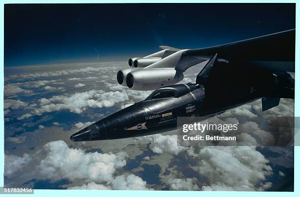 Tucked under the wing of a B-52 aircraft from which it is launched, this sleek X-15 research plane is poised for another of its many experimental...