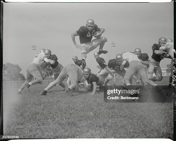 Bob Craig, Navy halfback, is shown going over the line of scrimmage during the Navy football team's practice session today. Craig, who hails from...
