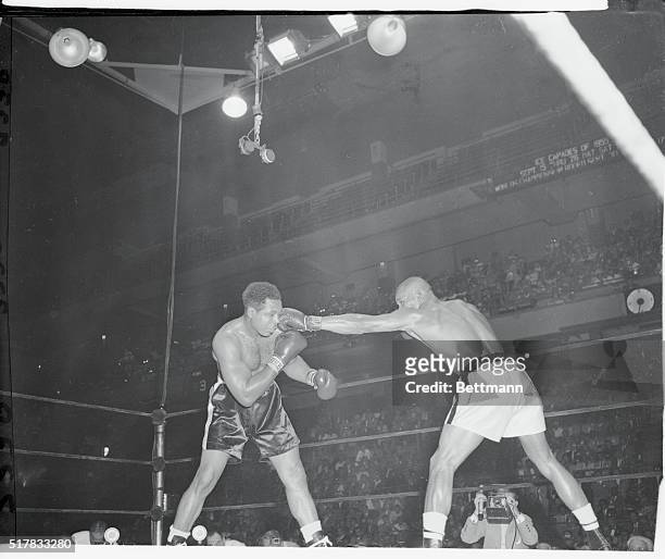 Challenger Harold Johnson connects with a long left to the face of light heavyweight king Archie Moore in the third round of their title bout at...
