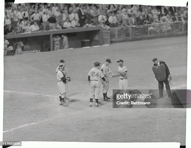Left fielder Al Smith of the Indians is shown being greeted at home plate by team mates George Strickland and Jim Hegan who rode home on his 7th...