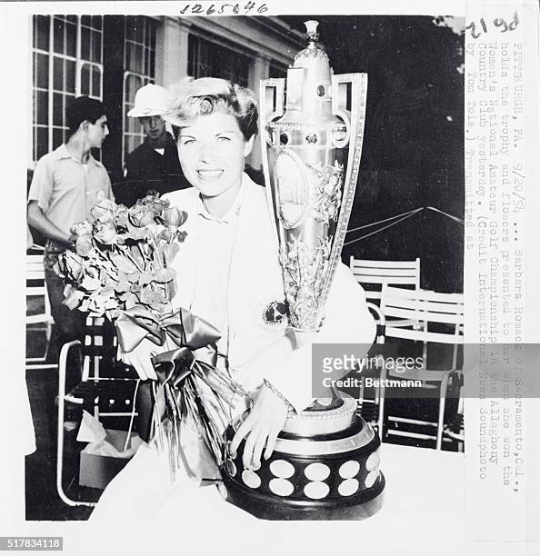 Attractive Barbara Romack, insurance saleswoman from Sacramento, Cal., is shown with the trophy and flowers presented to her after she defeated...