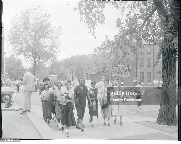 While two sign-carrying women pickets stand by, Negro students arrive at Baltimore's southern high school for classes. The Rev. Elder James L....