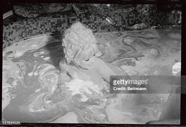 Mamie Van Doren gathers up a bunch of suds here to pour on her back, as she bathes in beer in a scene of her forthcoming movie Three Nuts In Search...
