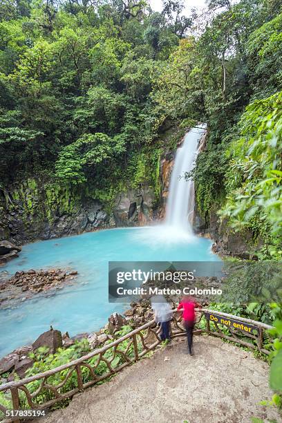 tourist couple looking at rio celeste waterfall, costa rica - parque nacional volcán tenorio fotografías e imágenes de stock