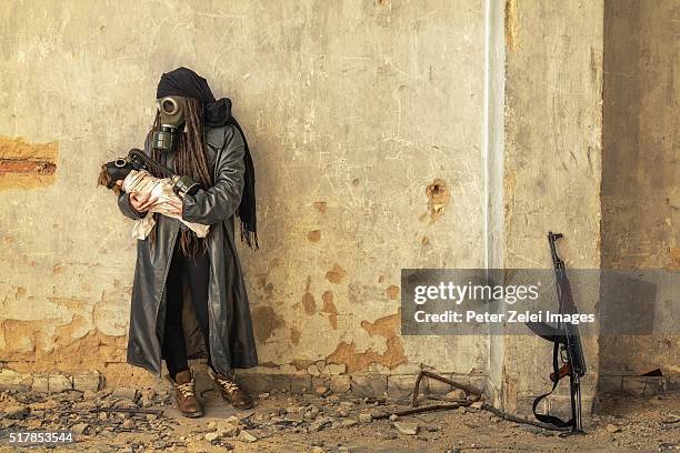 post apocalyptic survivor holding her baby in gas mask - grupo militante fotografías e imágenes de stock