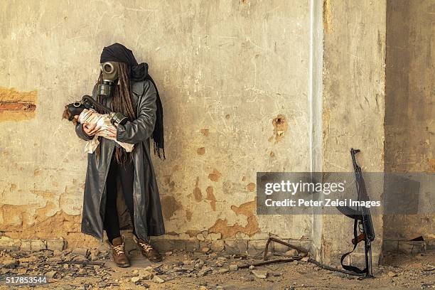 post apocalyptic survivor holding her baby in gas mask - kalashnikov stock pictures, royalty-free photos & images