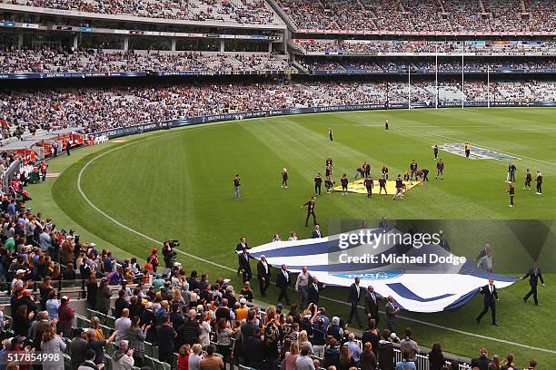Former Cats players walk around a large jumper with the number of deceased Cats player Paul Couch in tribute during the round one AFL match between...