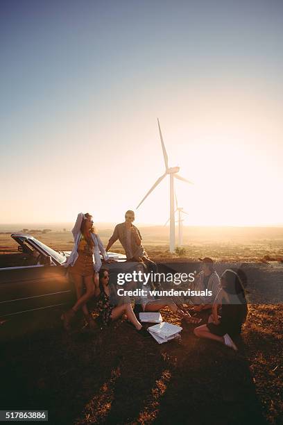 hipster friends eating pizza during road trip near convertible car - wind turbine california stock pictures, royalty-free photos & images
