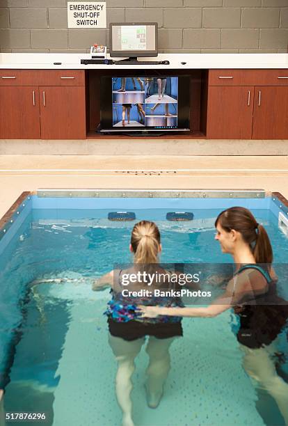 physical therapist assisting patient with hydrotherapy in a underwater treadmill - aquatic therapy stockfoto's en -beelden