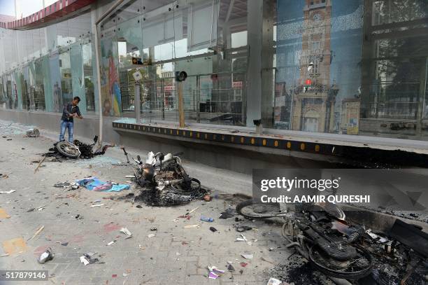 Pakistani bystander takes images of the wreckage of burnt-out motorbikes at a damaged Metro Bus station after an anti-government protest by the...