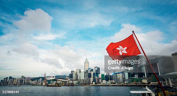 the hong kong flag flies over spectacular skyline - hong kong flag stock pictures, royalty-free photos & images