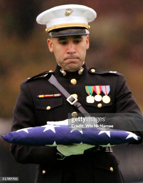 Member of the honor guard, presiding at the funeral service for U.S. Marine Corps Cpl. Nicholas L. Ziolkowski, carries a U.S. Flag at Arlington...