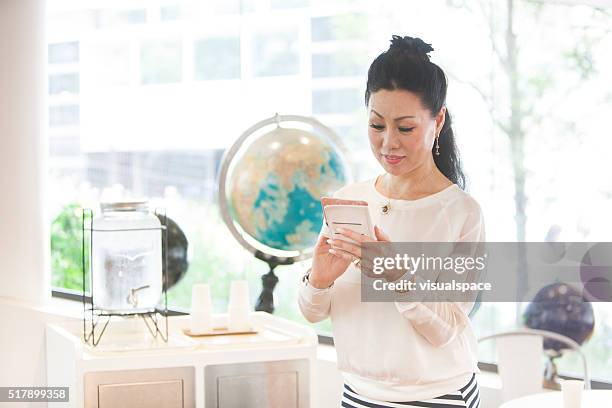 beautiful mature japanese woman texting on smartphone - world social media day stock pictures, royalty-free photos & images