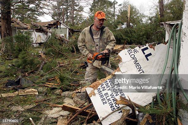 Tim Burris cuts up debris that fell on a friend's home in the aftermath of tornado damage on November 24, 2004 in Olla, Louisiana. Tornados swept...