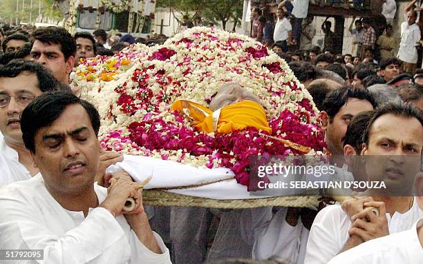 In this picture taken 07 July 2002, Mukesh and Anil Ambani carry the body of their father Dhirubhai Ambani, founder and chairman of India's largest...