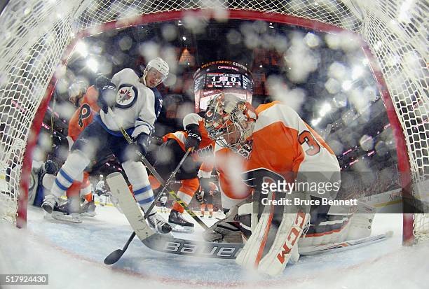 Steve Mason of the Philadelphia Flyers makes the save as Marko Dano of the Winnipeg Jets looks for the rebound at the Wells Fargo Center on March 28,...