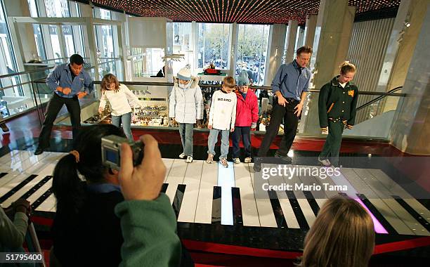 People play on a giant keyboard inside FAO Schwarz, the day after its grand re-opening November 26, 2004 in New York City. The Friday after...