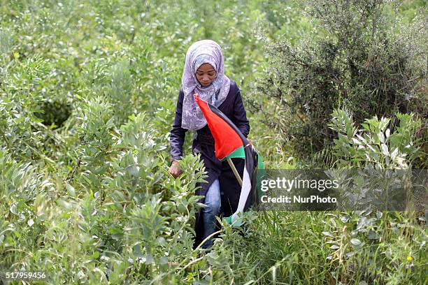 Palestinians hold national flags towards the Israeli border during a protest marking Land Day at the border between Israeli and Gaza Strip on March...