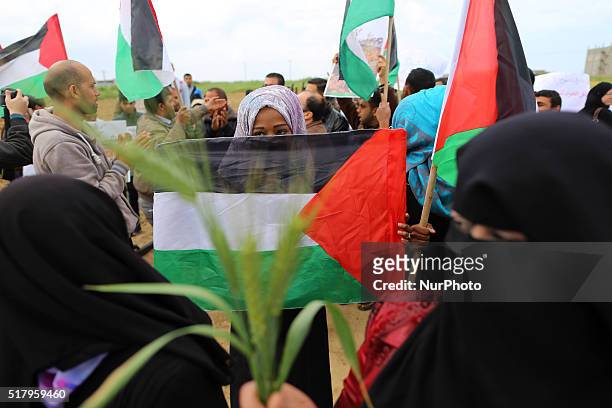 Palestinians hold national flags towards the Israeli border during a protest marking Land Day at the border between Israeli and Gaza Strip on March...