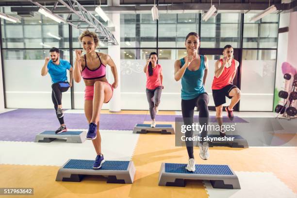 group of athletic people exercising step aerobics in a gym. - aerobic stockfoto's en -beelden