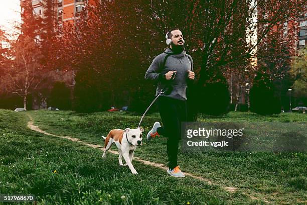 男 ジョギング、彼の犬となっています。 - 犬　走る ストックフォトと画像