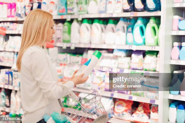 woman choosing fabric softener - wasmiddel stockfoto's en -beelden