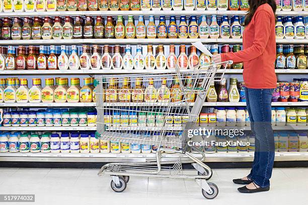 shopper checking list in supermarket aisle - shoppers ahead of consumer price index stockfoto's en -beelden