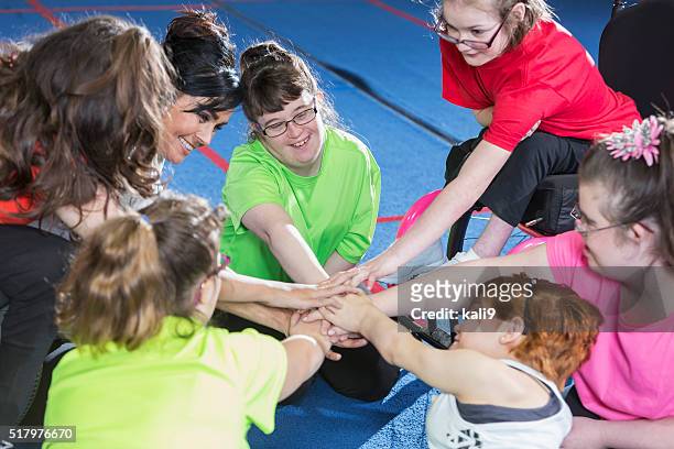 gruppo di bisogni speciali di ragazze mostrando spirito di squadra - bambini seduti in cerchio foto e immagini stock
