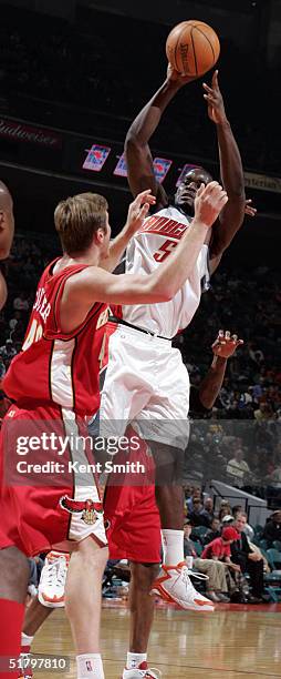 Emeka Okafor of the Charlotte Bobcats jumps high over Jason Collier of the Atlanta Hawks on November 27, 2004 at the Charlotte Coliseum in Charlotte,...