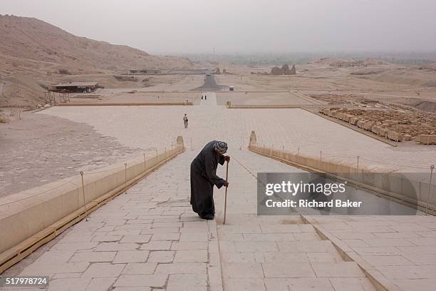 Caretaker sweeps dusty steps at the otherwise deserted ancient Egyptian Temple of Hatshepsut near the Valley of the Kings, Luxor, Nile Valley, Egypt....