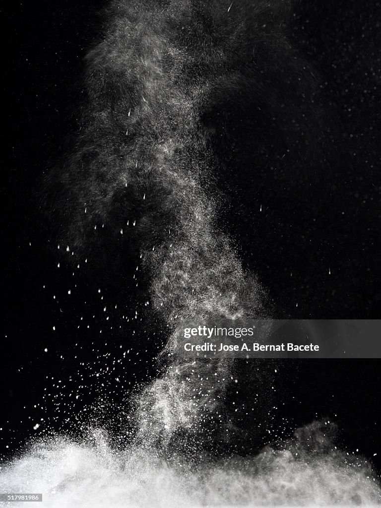 Blackground of particles of white powder in ascending movement floating in the air