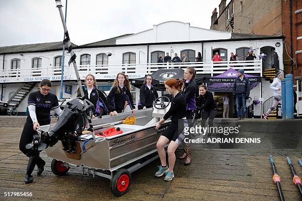 Putney High School girls wheel the coaches' dinghy down the boat ramp ahead of a training session outside their new boathouse in Putney, west London...