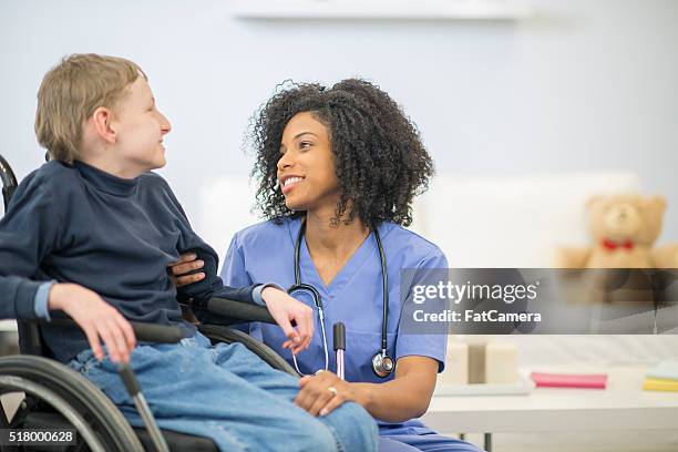 nurse talking to a disabled child - cerebal palsy stockfoto's en -beelden