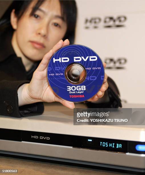 Japanese electronics giant Toshiba employee Junko Furuta displays the prototype model of the next generation DVD, "HD DVD" player and its 30GB disc...