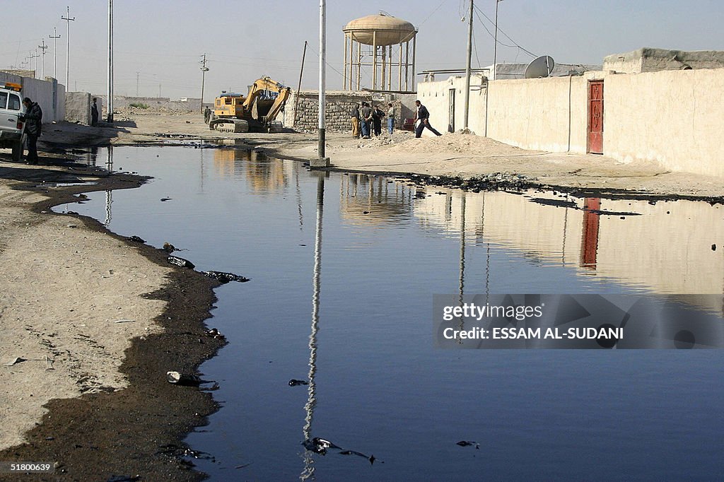 Iraqis gather at a pond of oil that leak
