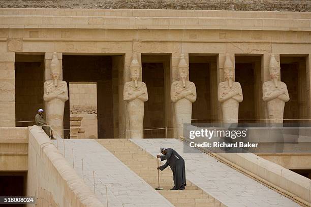 Caretaker sweeps dusty steps at the otherwise deserted ancient Egyptian Temple of Hatshepsut near the Valley of the Kings, Luxor, Nile Valley, Egypt....