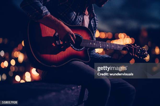 hipster-gitarristen spielen auf dem dach bei nacht - acoustic guitar stock-fotos und bilder