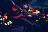 Hipster guitarist playing on a rooftop at night