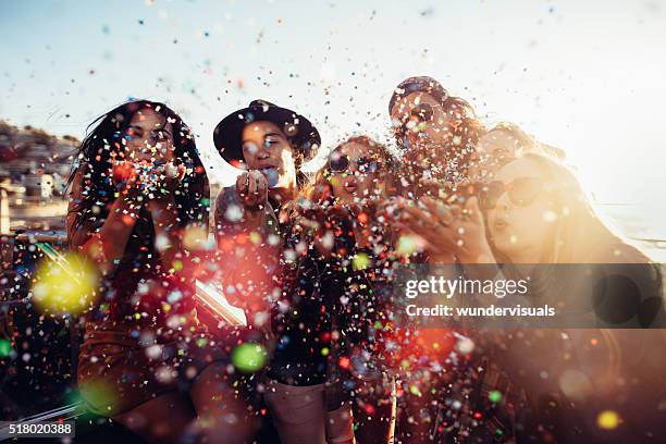 jugendlicher hipster freunde feiern von bunten konfetti geblasen aus den händen - girl beach sunset stock-fotos und bilder