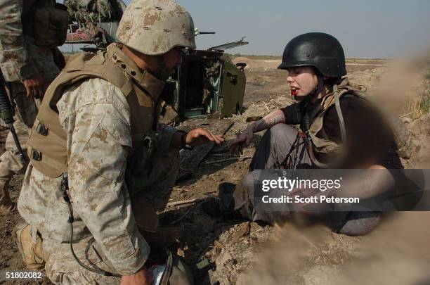 Navy medical corpsman Nick Navarrette helps wounded and diesel-drenched American freelance photographer Stephanie Kuykendal, as US Marines of the...