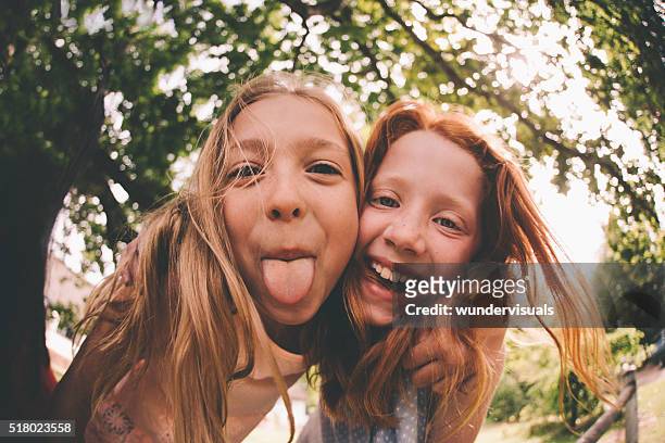 girls laughing and pulling faces at the camera in park - fish eye stock pictures, royalty-free photos & images