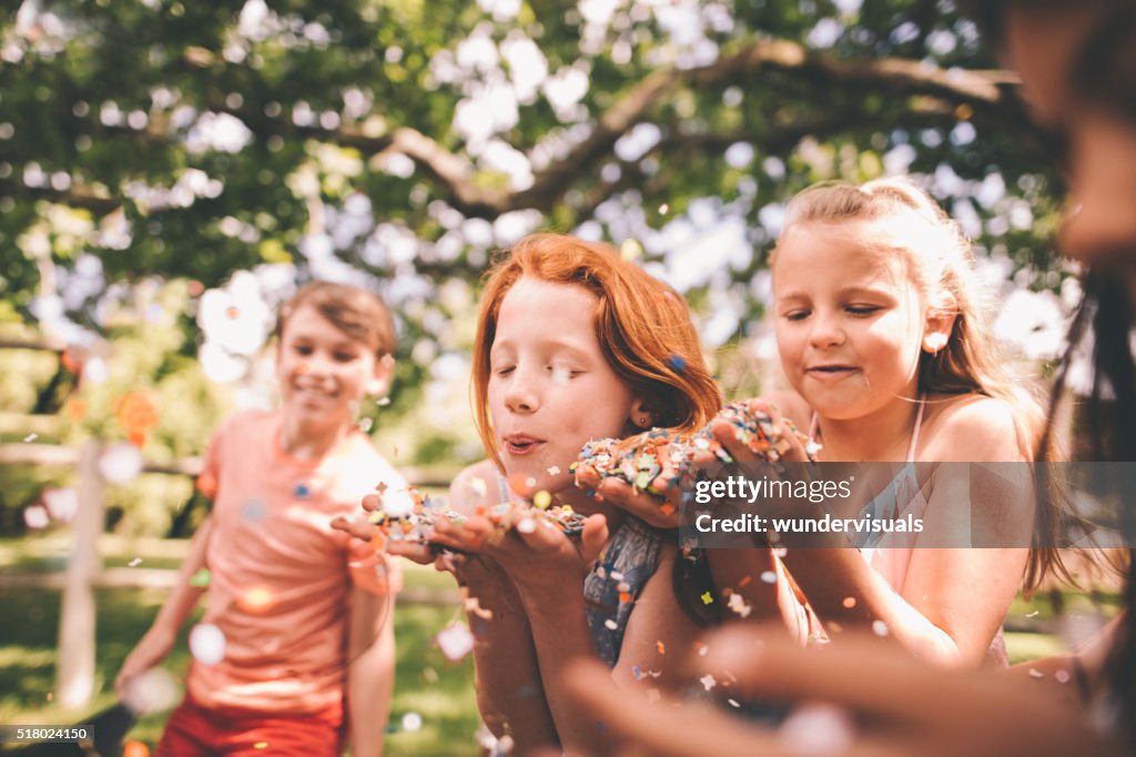 Children blowing colourful confetti in a sunny park