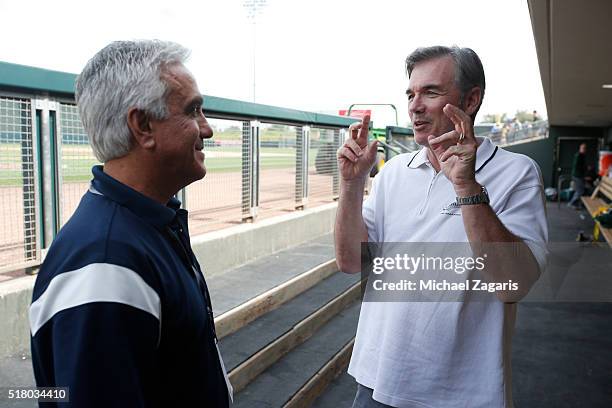 S Pedro Gomez talks with Executive Vice President of Baseball Operations Billy Beane of the Oakland Athletics in the dugout prior to a spring...