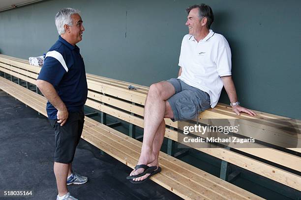 S Pedro Gomez talks with Executive Vice President of Baseball Operations Billy Beane of the Oakland Athletics in the dugout prior to a spring...